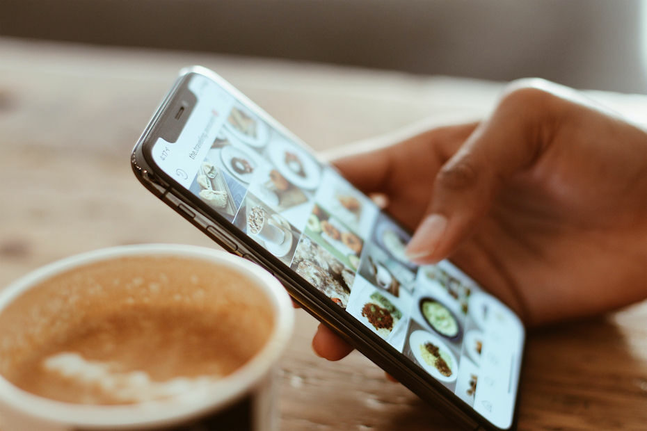 Smartphone showing food photos with person wondering how to get paid on Facebook and Instagram